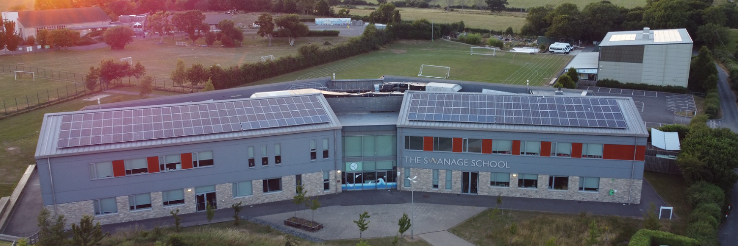 Overhead drone shot of The Swanage School at dusk showing the main school building grounds and sports hall