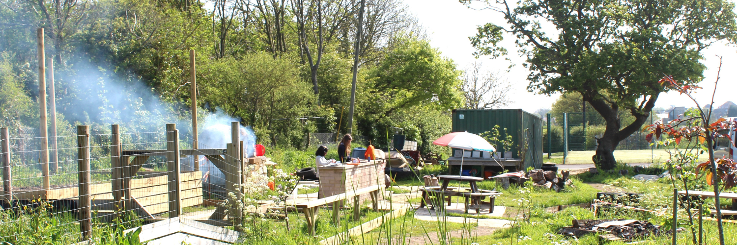 The Swanage Schools forest school area with trees picnic tables and a pizza oven