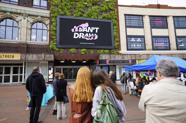 Crowd of people look at a big screen display with logo of Art Exhibition