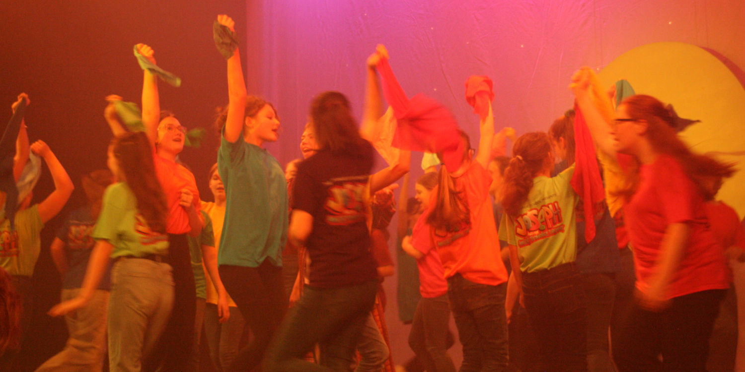 Ensemble dance in coloured t-shirt on stage in Joseph