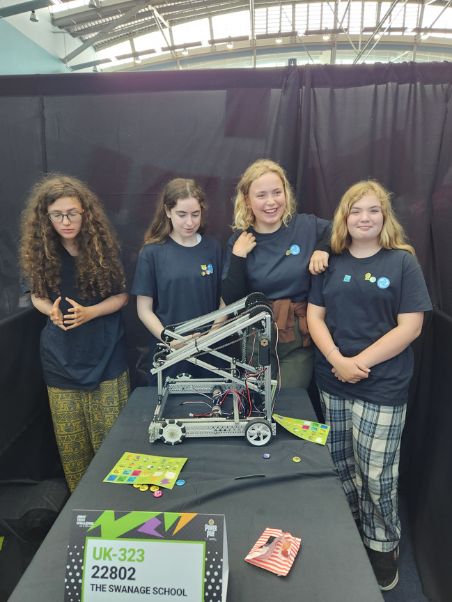 Four students in robotics team grey t-shirts pose for a photo