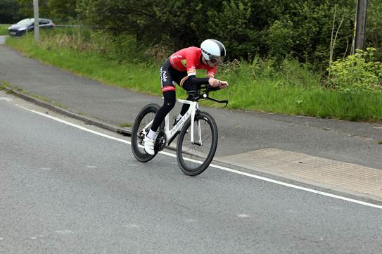 Young man in red cycling jersey competing in a road race time trial
